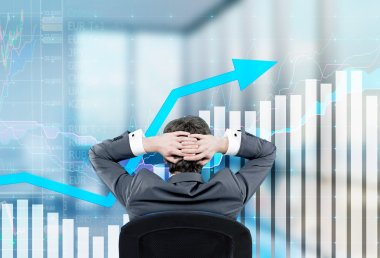Relaxing businessman sitting on the chair with hands on the back of his head. Image of semi-transparent graphs in front.