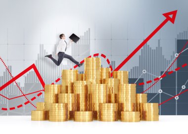 Young businessman with a black folder in hand running over a heap of golden coins, red graphs and grey bar charts behind.