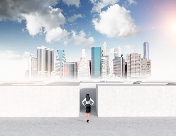 Young businesswoman with hands on hips standing in front of a concrete labyrinth. — ストック写真