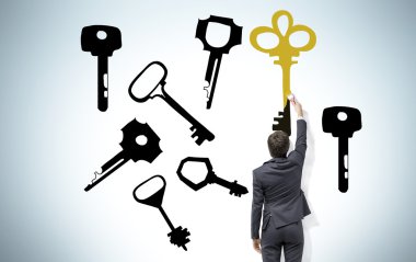 Young man painting keys on the wall with a brush that present the right solution.