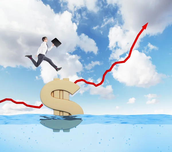 Young businessman running up a red painted graph on a sea background, blue sky, huge gold dollar sign afloat under him. — Stockfoto