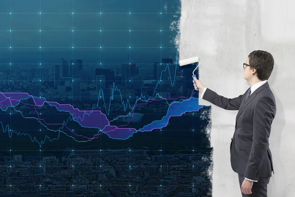 Young businessman painting a picture of New York city centre on a concrete wall with a roller as if it were a background for financial graphs. — Stockfoto