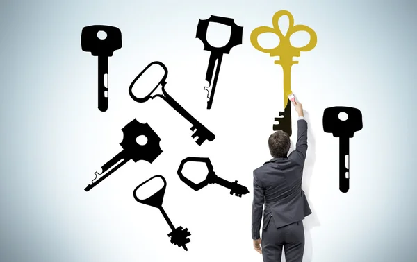 Young man painting keys on the wall with a brush that present the right solution. — Stok fotoğraf