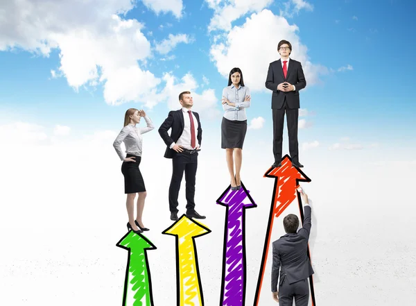 A businessman painting four red vertical arrows that are arranged as a bar chart, four people standing on them. — Stok fotoğraf