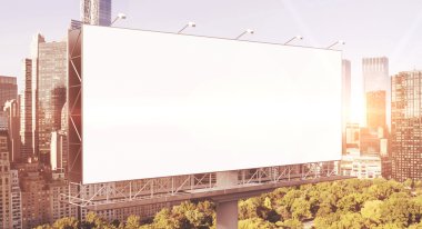 A huge blank billboard in the city centre at daytime.