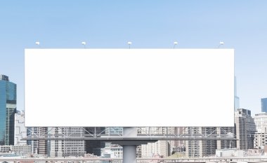A huge blank billboard in the city centre at daytime.