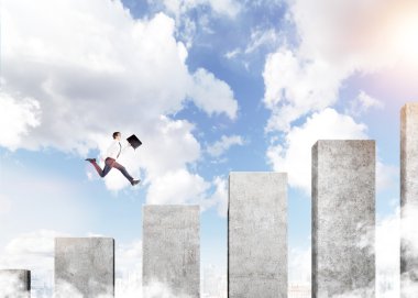 A young businessman running up a career ladder in shape of a concrete bar chart, blue sky at the background. Concept of career growth.