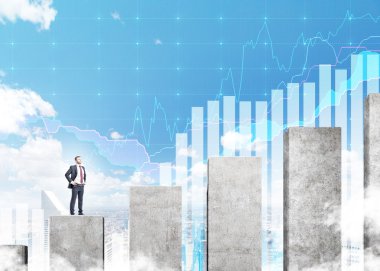 A young businessman standing on a career ladder in shape of a concrete bar chart, blue sky and blue graphs at the background.