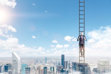 A young businessman in a suit climbing a ladder