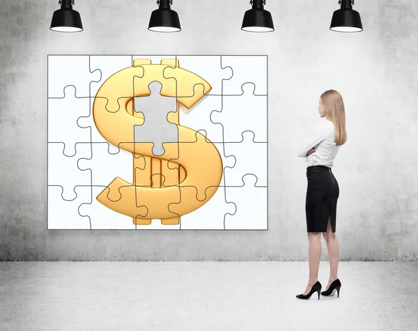Une femme d'affaires debout avec les bras croisés devant un puzzle sur le mur de béton avec une image de dollar d'or, une partie manquante, quatre lampes au plafond . — Photo