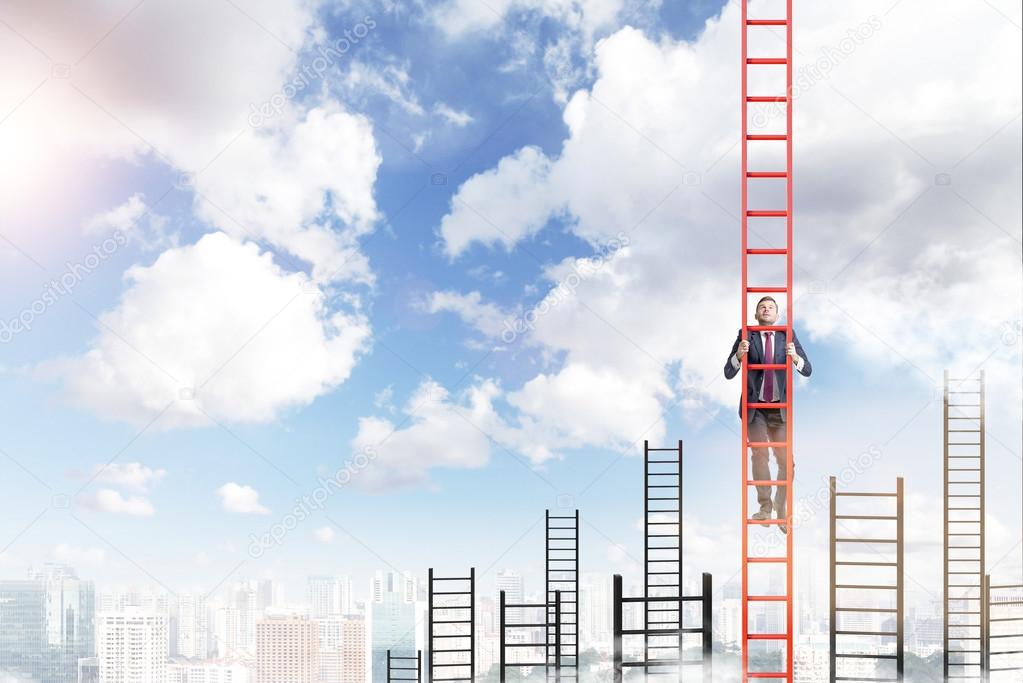 A young businessman in a suit climbing a ladder