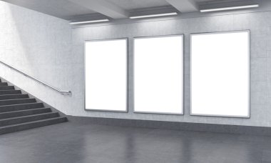Three vertical billboards in the underground, stairs up to the left.