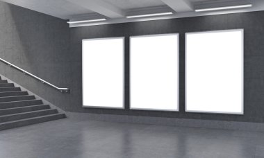 Three vertical billboards in the underground, stairs up to the left.