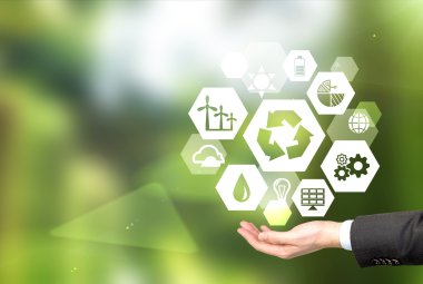 hand holding signs of different green sources of energy in hexahedron shape, a 'reduce, reuse, recycle' sign in the centre.
