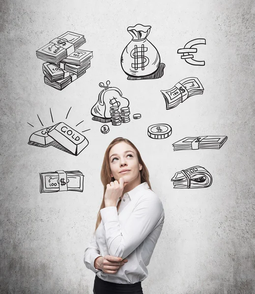 Beautiful woman with hand on chin looking up and thinking about money, black pictures symbolizing money over her head. — Stockfoto