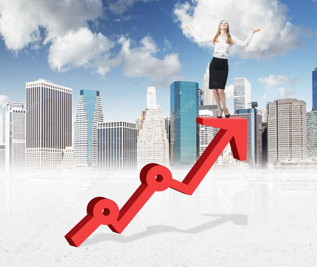 A smiling young woman standing on a thick red growing graph looking up with her hands raised. New York and blue sky at the background.