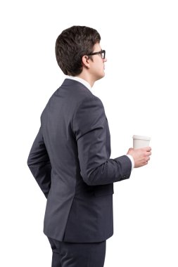 A young man in a black suit holding a paper cup. White background. Concept of coffee break. Isolated