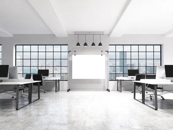 Two rows of computer tables in a light modern open space office, a big blank screen on the wall between the windows with Paris view, four lamps over it. — Zdjęcie stockowe