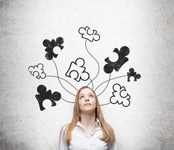 Красивая молодая женщина, стоящая у бетонной стены с нарисованными на ней частями головоломки, глядя вверх
.