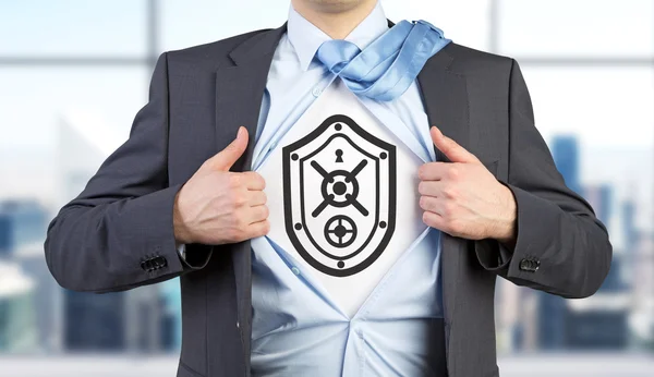 Um homem com uma camisa desabotoada com uma imagem de escudo que se assemelha a uma porta segura no peito. Vista frontal . — Fotografia de Stock