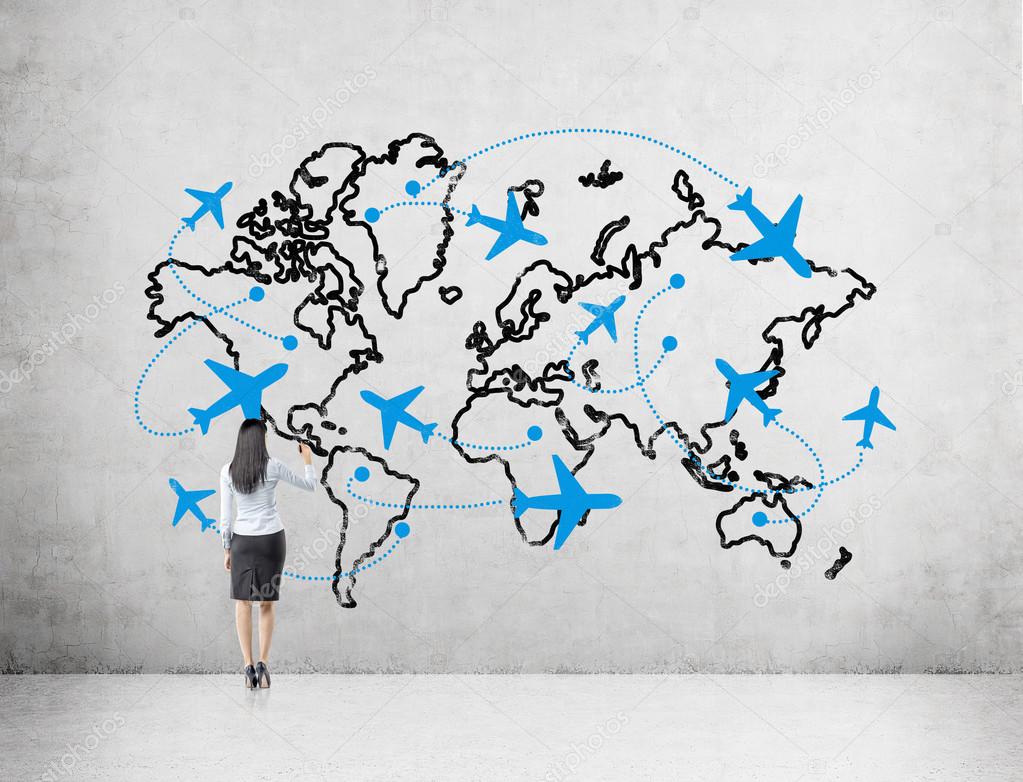 A woman drawing a map demonstaring flight destinations around the globe on a concrete wall in front of her.