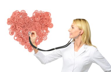 A young female doctor in a white smock holding a phonendoscope and listening to a huge heart made of coral cogwheels.
