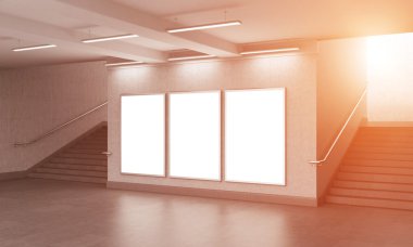 Three blank vertical billboard in the underground crossing, stairs up on both sides, loght seen from the street.