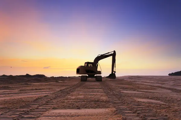 excavators dinging sand at beach silhouette