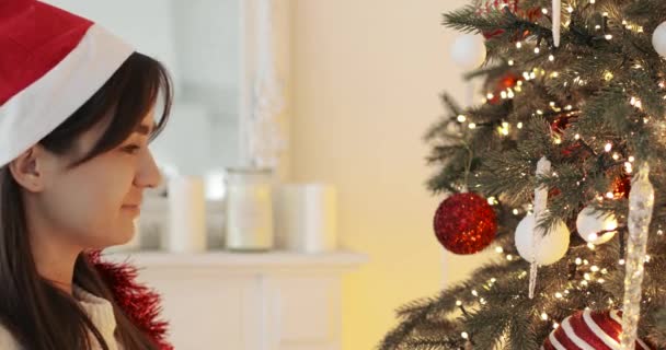 Retrato de mujer feliz mirando juguetes en un árbol de Navidad y los toca. — Vídeo de stock