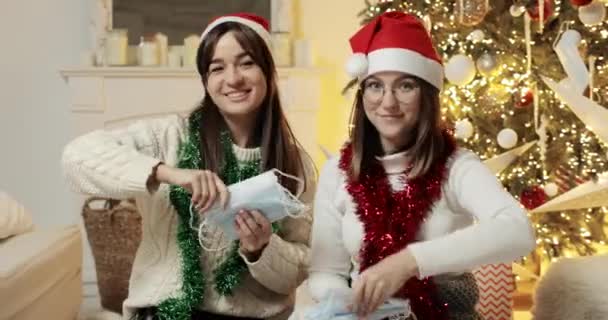 Les jeunes femmes jettent des masques médicaux près de l'arbre de Noël en regardant la caméra. — Video