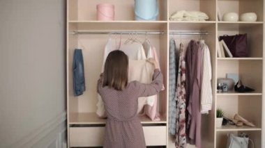 Genç kadın giyecek bir şeyler bulmak için dolaptan bir şeyler atıyor..