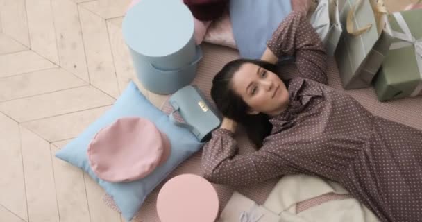 Mulher shopaholic está deitado no chão cercado por caixas, bolsas e roupas. — Vídeo de Stock