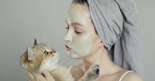 可爱的蓝眼睛女孩，洗澡后抱着猫，戴着黏土面具 — 图库视频影像