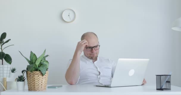 若い男がノートパソコンの前に座って考えている。正面図. — ストック動画