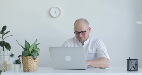 Młody człowiek siedzi przed laptopem i pracuje. Widok z przodu. — Wideo stockowe