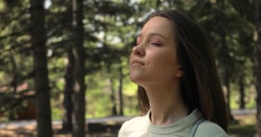 Güneşli bir günde parkta oturan ve gülümseyen çekici bir kadının portresi. Mutlu ve güzel bir kadının yüzü