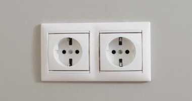 Kadınlar beyaz elektrik prizini kapalı alanda birden fazla sokete takıyor..