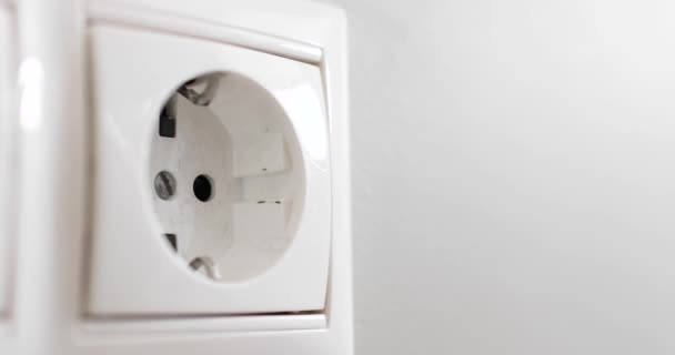 Plugue de energia preto plugue mão em tomada múltipla branca dentro de casa. — Vídeo de Stock