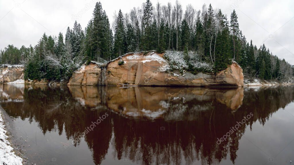 panoramic view of sandstone outcrop on the opposite bank of the river, river gauja in December, Cesis, Erglu cliffs, Latvia