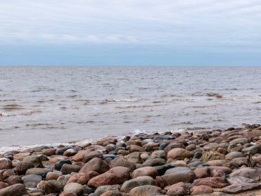 Akşamları kayalık plajlı manzara, bulutların arkasında saklanan güneş, güzel gökyüzü.