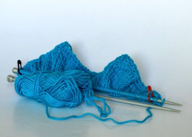 İplik üzerinde metal iğneler olan parlak mavi örgü, zevk için el işi, örgü konsepti, el yapımı