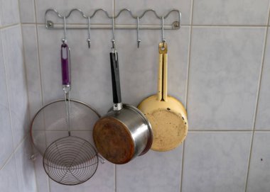 Duvardaki askıda çeşitli mutfak gereçleri, yemek pişirme konsepti.