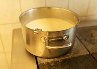 Ocağın üstünde süt çorbası, okul mutfağı, yemek pişirme konsepti, metal mutfak tenceresi olan metal kap.