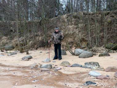 Taşlı plajlı manzara ve akşamları yalnız adam silueti, bulutların arkasında saklanan güneş, güzel gökyüzü.