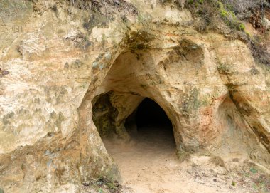 Kum taşı duvar ve mağaranın girişi, mağara Priedaine Mağarası, Cesu Bölgesi, Letonya 'da küçük bir nehrin kıyısında yer almaktadır.