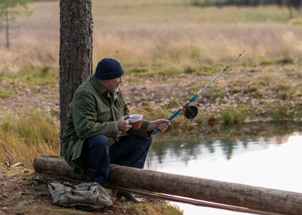 川沿いの漁師は木の枝に座ってお茶を飲んだり背景をぼかしたり秋の時間 — ストック写真