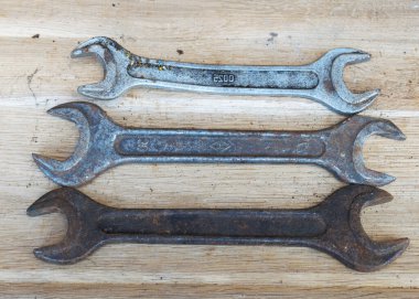 Ahşap arka planda antik anahtarlar, paslı aletler, metal atıkları, hurda metaller, İngiliz anahtarı koleksiyonu.