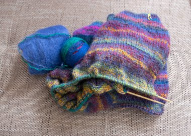 Renkli batik ipliklerden örülmüş kazaklar, ahşap iğneler ve iplik topları, hafif arka plan, el yapımı örgü konsepti, hobi