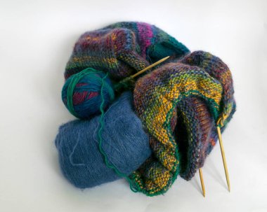 Renkli batik ipliklerden örülmüş kazaklar, ahşap iğneler ve iplik topları, hafif arka plan, el yapımı örgü konsepti, hobi