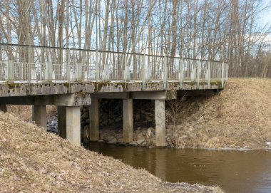 Beton köprülü manzara, ilkbaharın başlarında, çıplak ağaçlar, yerde kar planı, Kuja nehri, Madona, Letonya